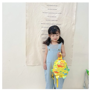 Detailed view of yellow toddler dinosaur backpack with cartoon prints and dual zippers