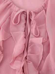 Nahaufnahme des rosa Chiffonkleid-Ausschnitts mit Rüschenkanten und Bindeband-Detail
