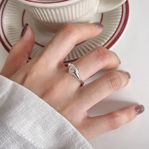 Macro shot of minimalist silver heart-shaped zircon ring worn by a model in lifestyle setting