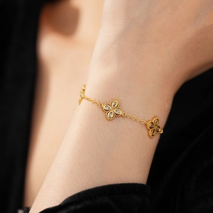 Detail showing gold floral bracelet with zircon accents worn on a female wrist