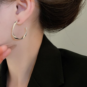 Close-up of minimalist silver twisted hoop earrings on model for a modern commute style