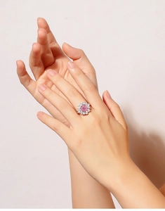 On-hand display of a silver ring featuring a pink heart-shaped zircon and white stones