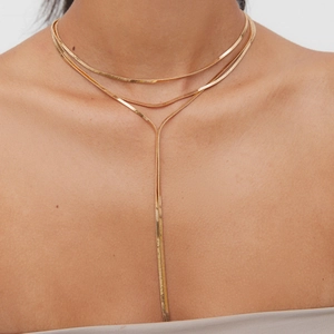 Detail of a gold double-layer Y-shaped metal necklace worn by a model for a chic look