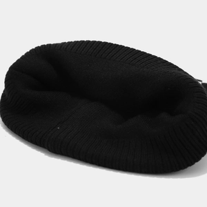 Détail d'un bonnet en maille côtelée noire montrant la texture et la couture du haut