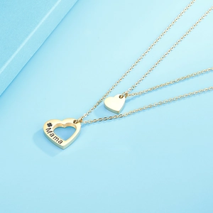 Gros plan d'un collier doré double épaisseur avec gravure Mama et pendentif cœur