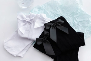 Detail view of JK uniform socks featuring large satin bows in white and black colors