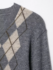 Macro shot of V-neck knitted sweater with grey argyle pattern and soft wool texture