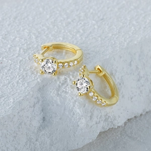 Close-up of gold-plated silver hoop earrings with classic four-prong diamond setting