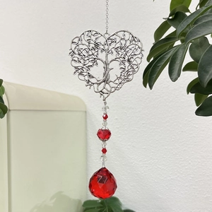 Detail of red crystal heart tree of life suncatcher hanging in a home garden setting
