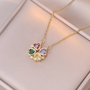 Macro shot of gold-plated necklace with four-color crystal heart clover pendant on satin
