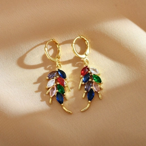 Close-up of golden leaf earrings with multi-color marquise gemstones on silk background