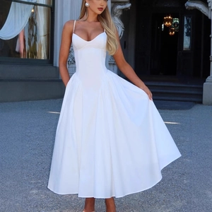 Robe longue blanche élégante avec col en V et bretelles fines devant une villa