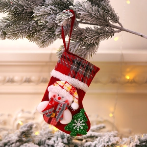 Close-up of a red fabric Christmas stocking with 3D snowman and sequined tree on pine branch
