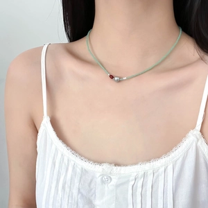 Détail d'un collier de perles avec agate rouge et perles vertes sur le cou du mannequin
