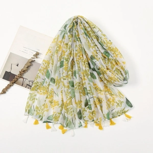 Close-up of lightweight white scarf with yellow floral prints and delicate fringe details