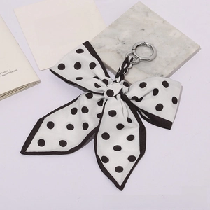Close-up of black and white polka dot ribbon bow keychain with a silver metal ring