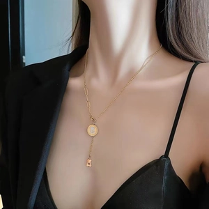 Golden bear pendant necklace with ball and link chain design worn by a model