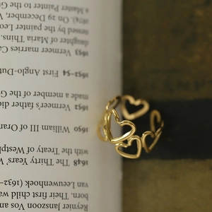 Détail d'une bague dorée ajourée en forme de cœur sur un fond de livre ancien