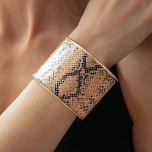 Close-up of wide cuff bracelet with gold metal edges and brown snakeskin texture