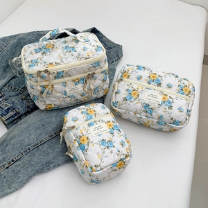 Three-piece quilted floral makeup bag set with yellow and blue flowers on white fabric
