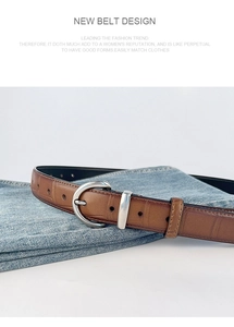Detailed view of a brown crocodile texture leather belt with a silver D-ring buckle on denim