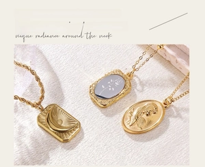 Macro shot of vintage gold embossed pendants with moon and rose patterns on textured fabric