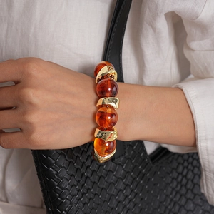 Dettaglio di perline in acrilico ambrato e accenti in metallo dorato su bracciale vintage