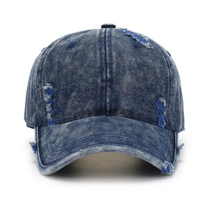 Distressed dark blue denim baseball cap with vintage frayed holes and washed finish