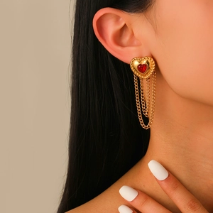 Golden heart earrings with red gemstones and tassel chains worn by a female model