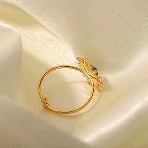 Gold sunburst open ring with green turquoise inlay on white silk fabric background