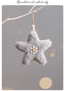 Detail of plush grey star ornament with wooden snowflake and hemp rope hanging on a branch