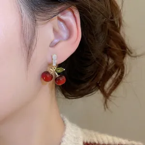Élégantes boucles d'oreilles cerise en résine rouge avec feuilles en zircon sur mannequin
