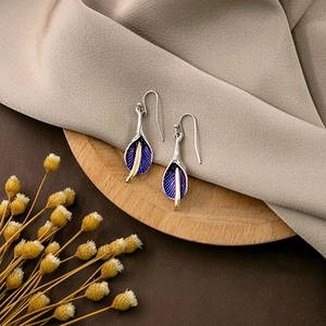 Artistic calla lily hook earrings with purple enamel and golden pistils on wood