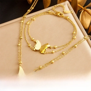 Macro shot of gold butterfly necklace and bracelet set on premium silk texture