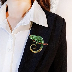 Green enamel chameleon brooch with crystals pinned on a black suit jacket lapel