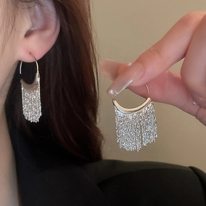 Vue détaillée des boucles d'oreilles pendantes à pompons argentés avec chaînes fines