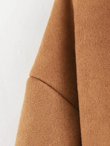 Macro shot of thick caramel wool fabric showing detailed shoulder seam and texture