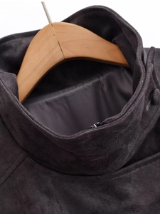 Gros plan sur la fermeture éclair métallique et le col montant d'une veste en daim gris foncé