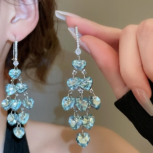 Detailed close-up of blue heart crystal tiered tassel earrings with silver rhinestones