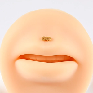 Macro shot of gold infinity symbol labret stud worn on a silicone model's upper lip