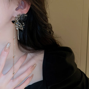 Macro detail of black butterfly fringe earrings with long silver chains on a model