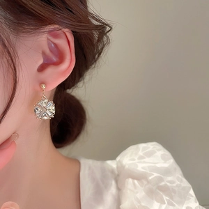 Gros plan d'une élégante boucle d'oreille fleur plaquée or avec zircons sur le mannequin