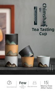 Macro detail of Zen-style ceramic tea cups showing mountain patterns and raw clay texture