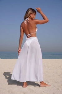 Rear view of a woman in a white bikini and sheer mesh maxi skirt on a sunny beach