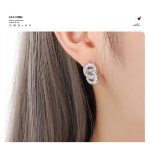 Close-up of elegant silver double hoop earrings with woven texture and micro crystals
