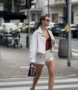 Close-up of white polka dot cropped jacket and shorts set with a deep red bucket bag