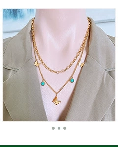 Detail of double-layer gold butterfly necklace with green beads worn on a neck