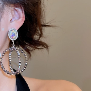 Détail de boucles d'oreilles longues à double perle avec pierres irisées et zircons
