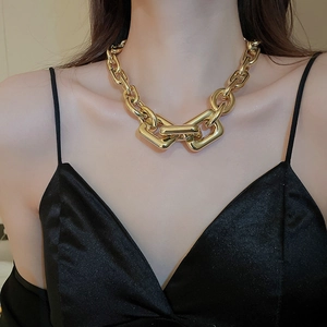 Close-up of chunky gold geometric chain necklace worn with a black silk dress