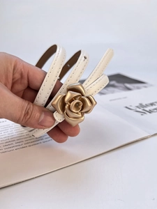 Detailed view of white genuine leather thin belt featuring a gold 3D rose flower buckle